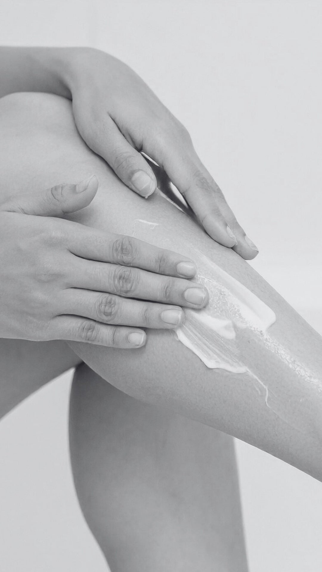 Person applying cream to their leg with a neutral background