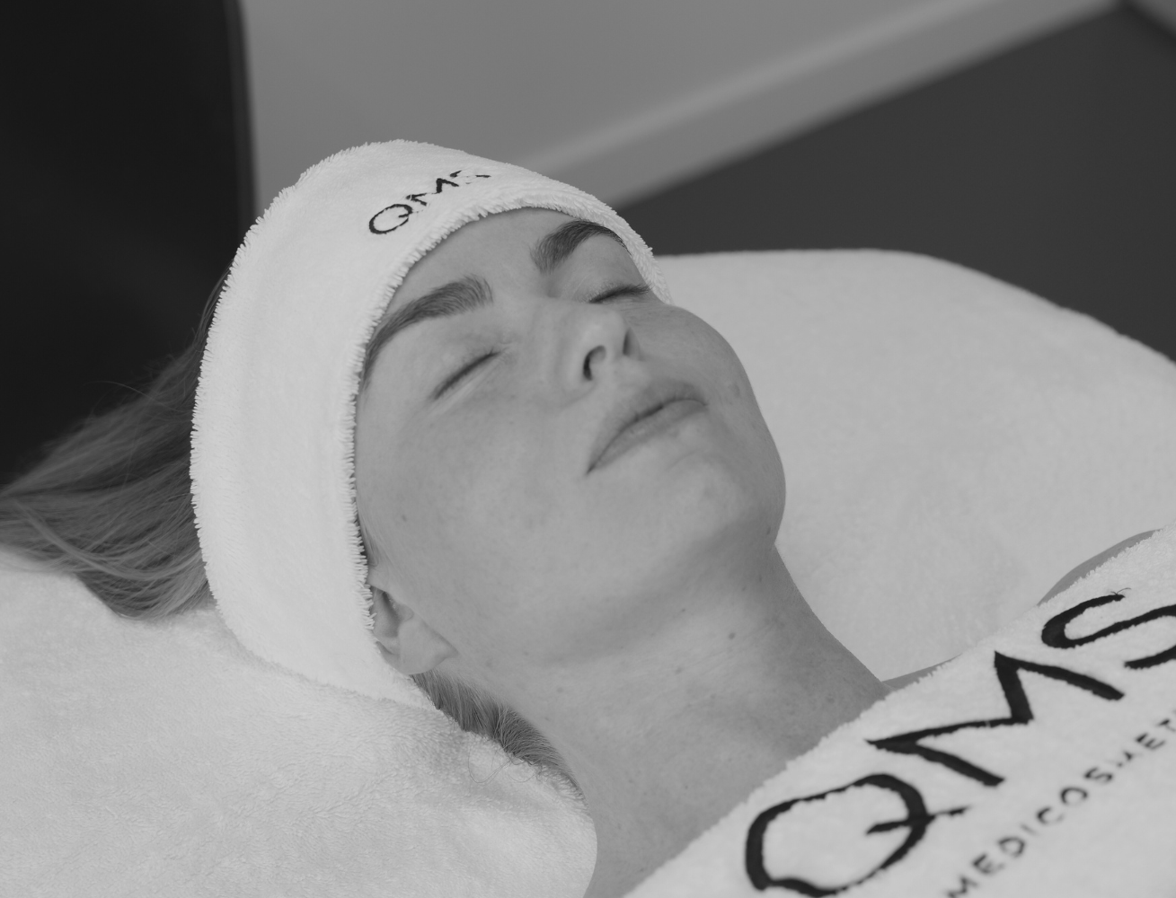 Person receiving a facial treatment with 'QMS Medispa' branding.